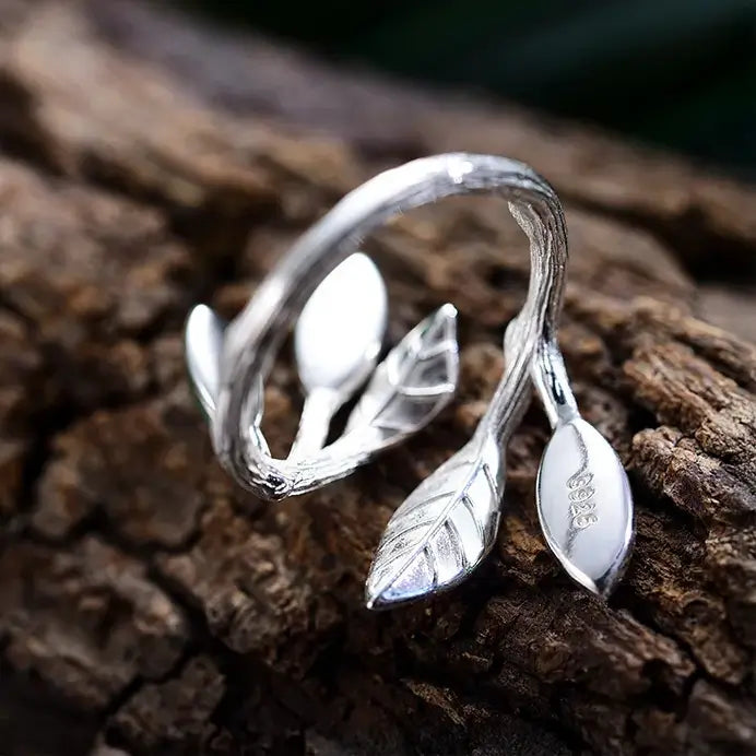 Bague feuillage en argent 925 posée sur écorce de bois, aventurine verte évoquant une rosée végétale.