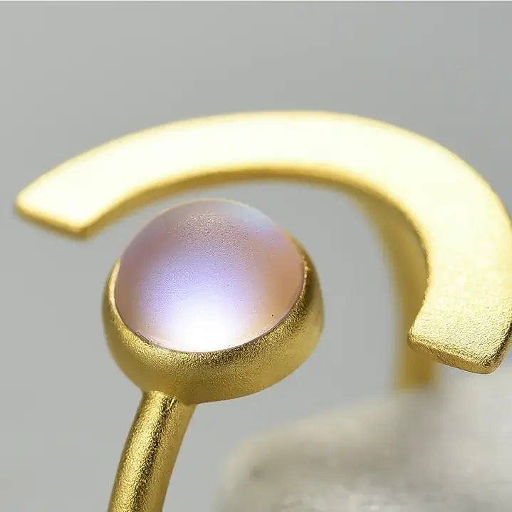 Gros plan sur l’émail glacé de la bague Lune de Terre, reflet nacré et texture mate en argent 925 doré.