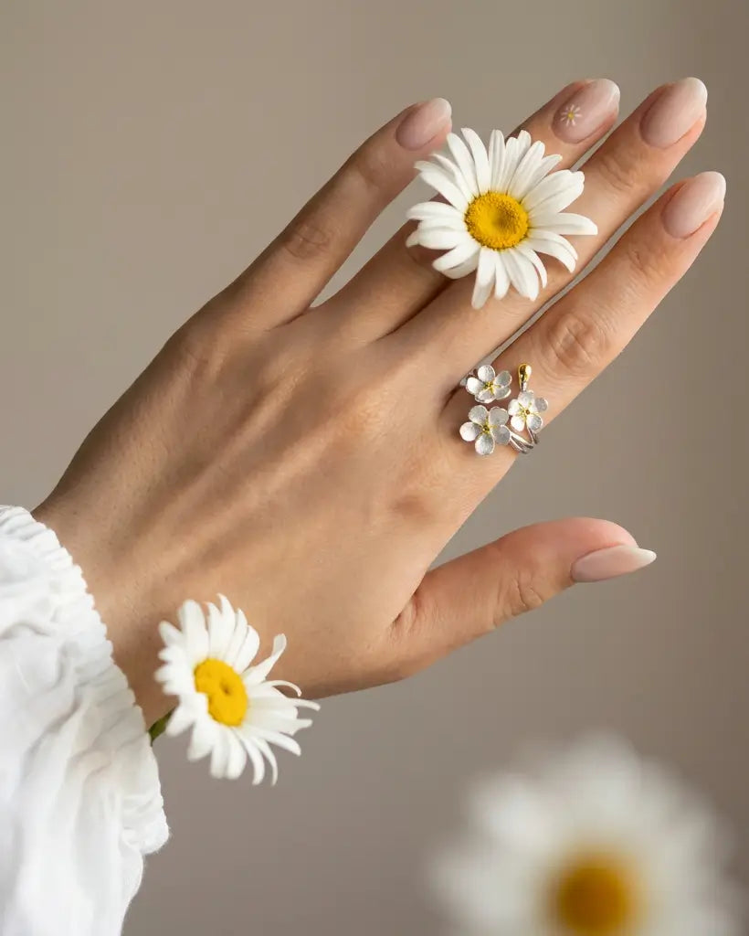 Bague trois fleurs argent 925 portée à la main, inspirée d’un bouquet floral printanier et élégant.