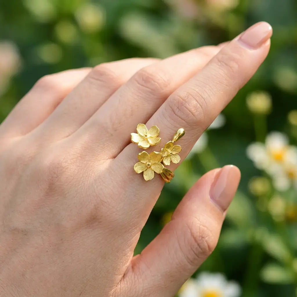 Bague trois fleurs argent 925 portée sur la main, ambiance naturelle et florale.
