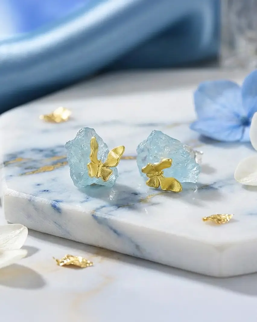 Boucles d’oreilles en argent 925 avec pierres bleues naturelles, mises en scène sur une surface minérale aux tons célestes.