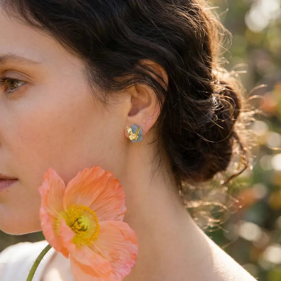 Détail des boucles d’oreilles en argent 925 avec pierres bleues portées à l’oreille, design délicat et organique.