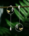 Boucles d’oreilles asymétriques Chant du Matin en argent 925 suspendues dans un décor végétal, inspirées du chant des oiseaux à l’aube.