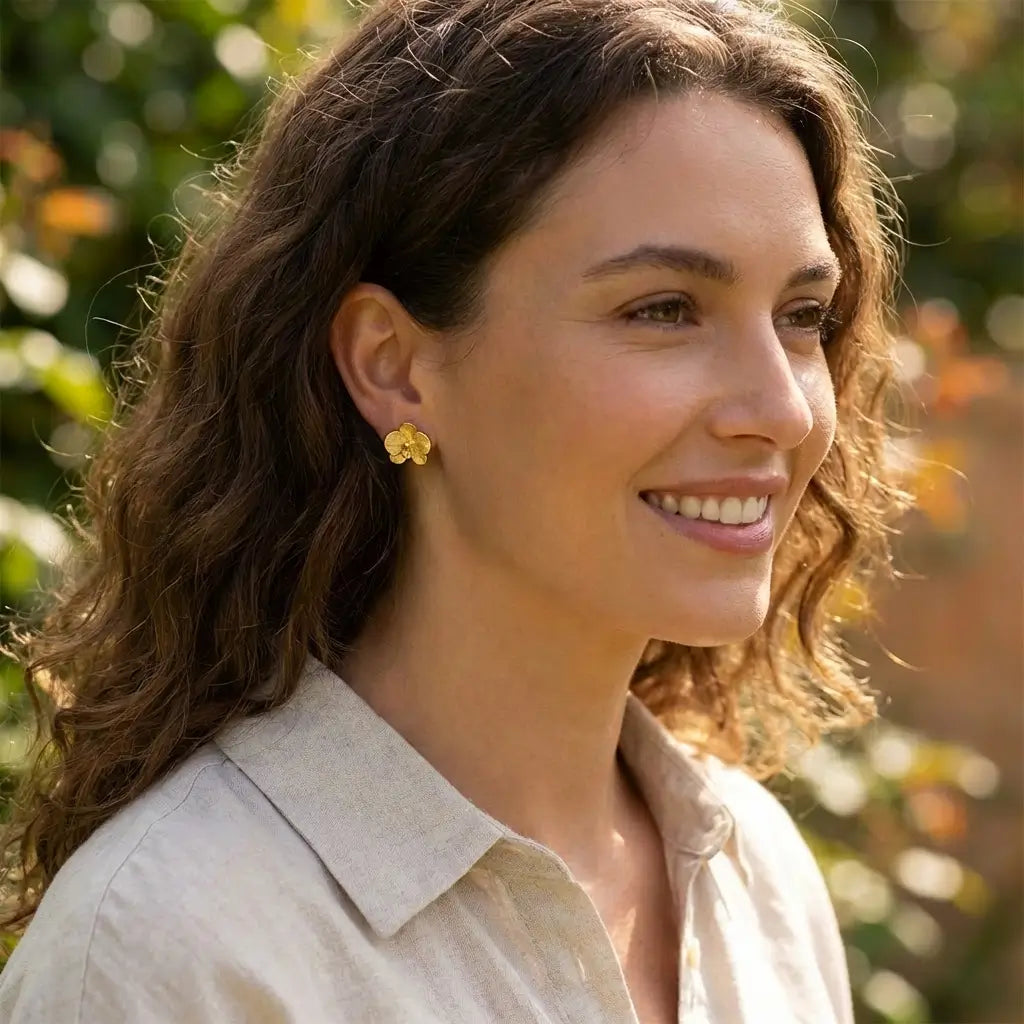 Boucles d’oreilles orchidées en argent 925 avec finition dorée portées par une femme, bijou floral inspiré de la nature.