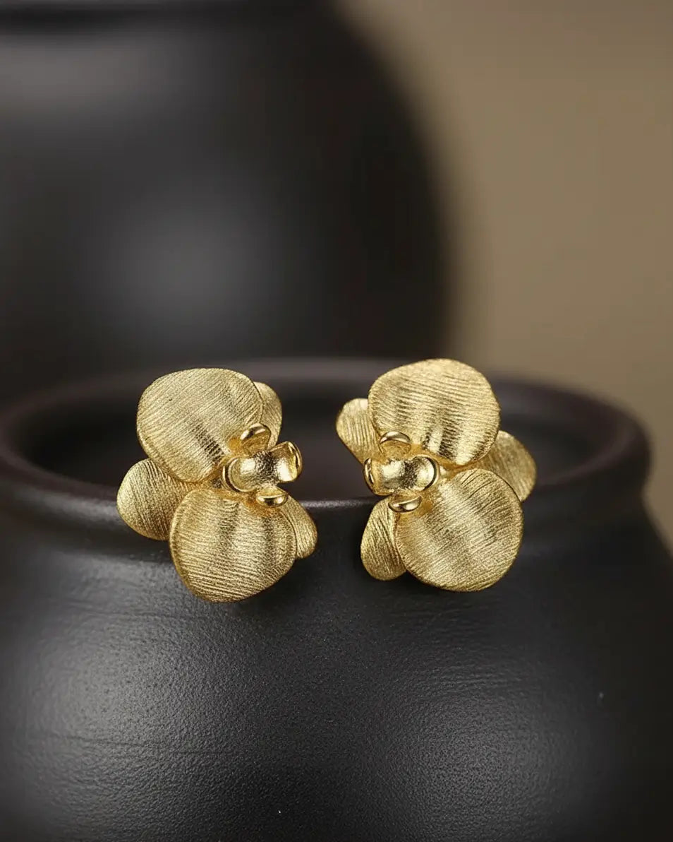 Boucles d’oreilles orchidées en argent 925 à finition dorée présentées sur fond sombre, mettant en valeur le relief floral.