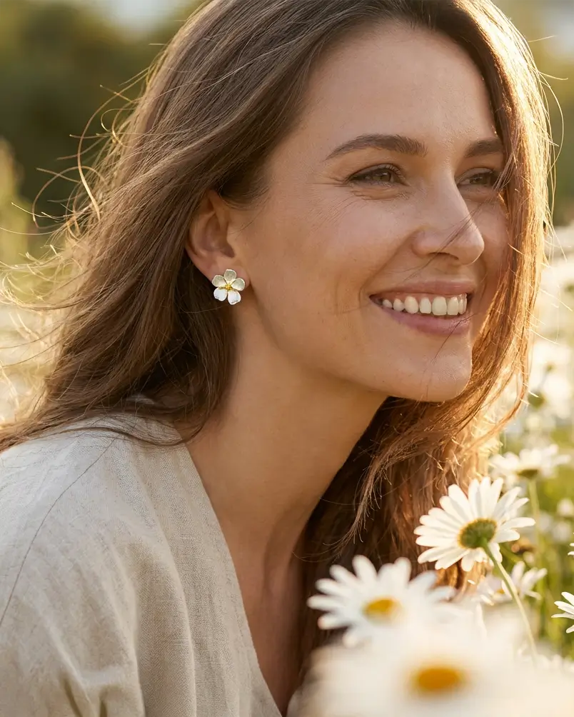 Boucles d’oreilles pâquerette en argent avec cœur doré et émail blanc portées par une femme, style naturel et élégant.