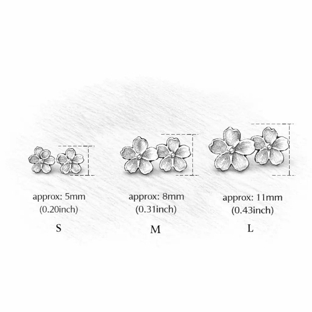 Guide des tailles des boucles d’oreilles pâquerette en argent doré et émail blanc, avec dimensions S, M et L.