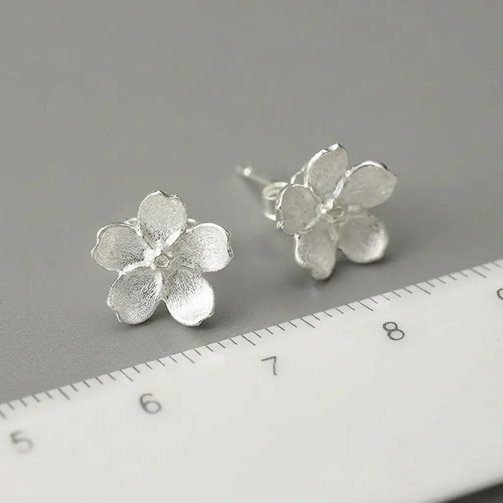 Boucles d’oreilles pâquerette en argent et émail blanc avec indication précise des dimensions sur règle.