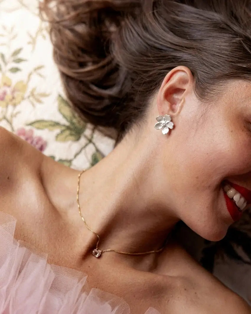 Boucles d’oreilles pâquerette en argent et émail blanc portées par une femme, style élégant et lumineux.