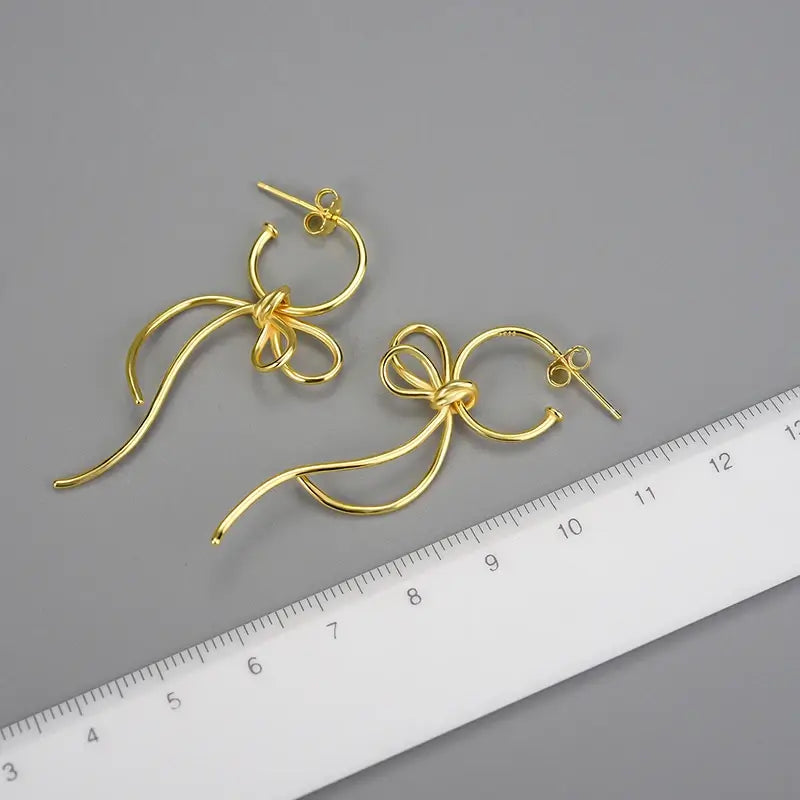 Boucles d’oreilles volutes argent 925 finition or présentées avec règle pour visualiser la taille réelle.