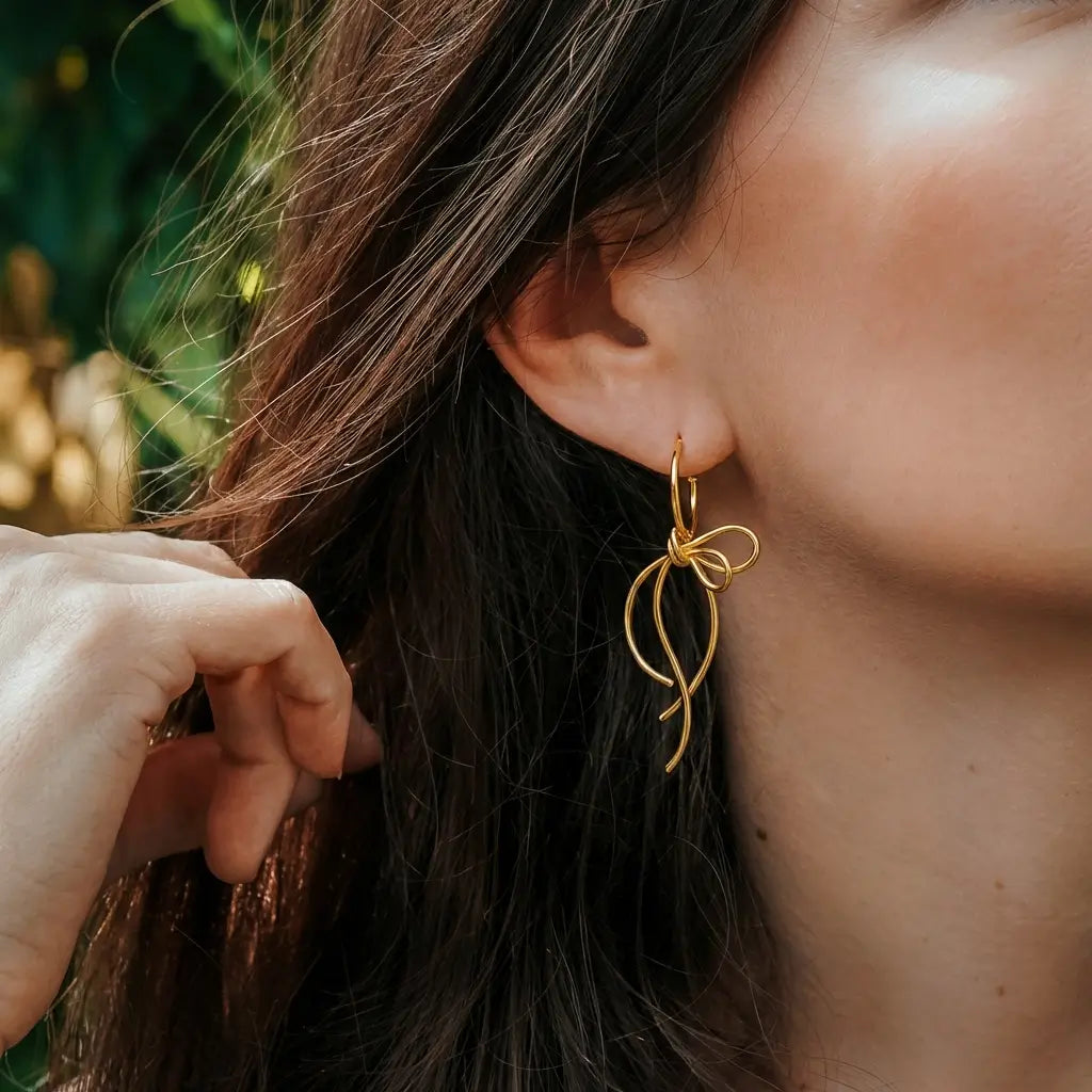 Détail des boucles d’oreilles volutes argent et or portées à l’oreille, design fluide et féminin.
