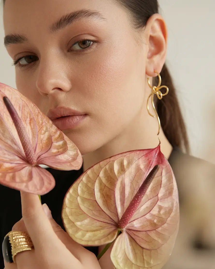 Boucles d’oreilles volutes argent et or portées, ambiance lifestyle florale et naturelle, bijou élégant et aérien.