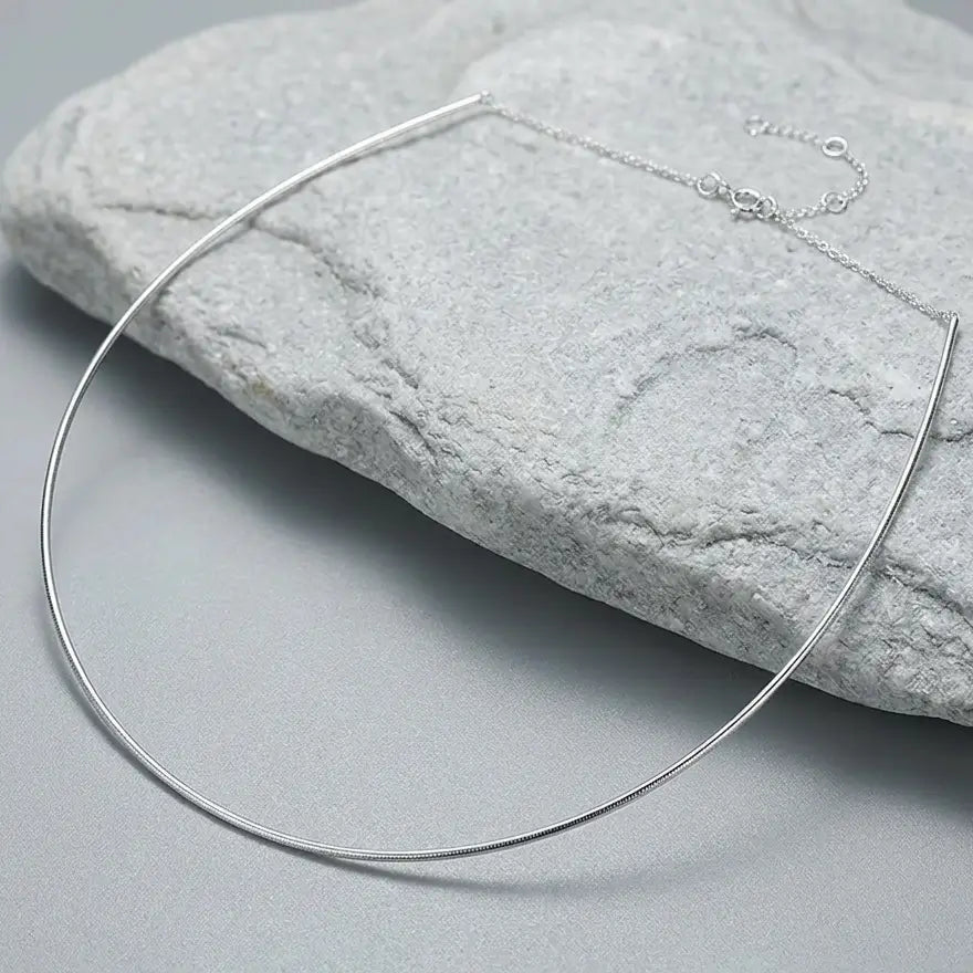 Chaîne torque rigide en argent 925 présentée sur une pierre minérale naturelle