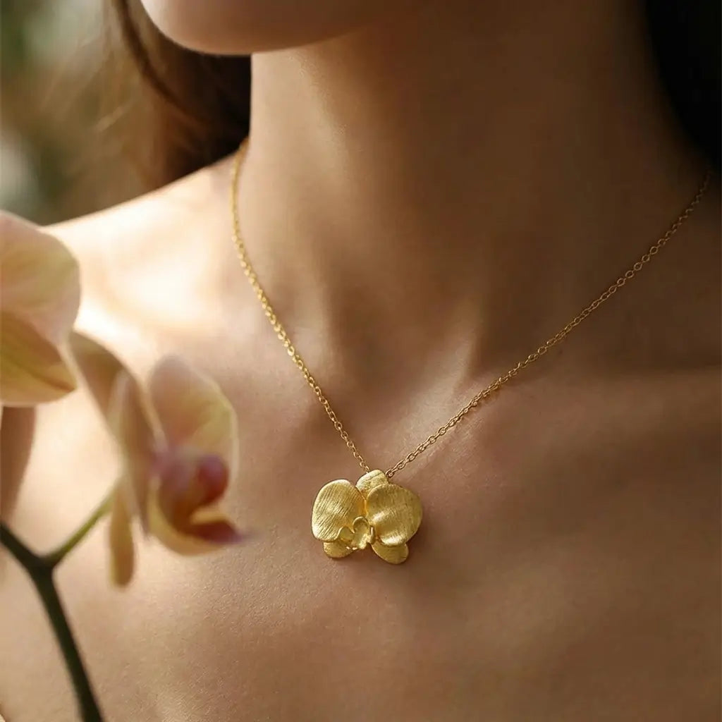Collier orchidée en argent 925 avec finition or porté au cou, bijou floral élégant et féminin.