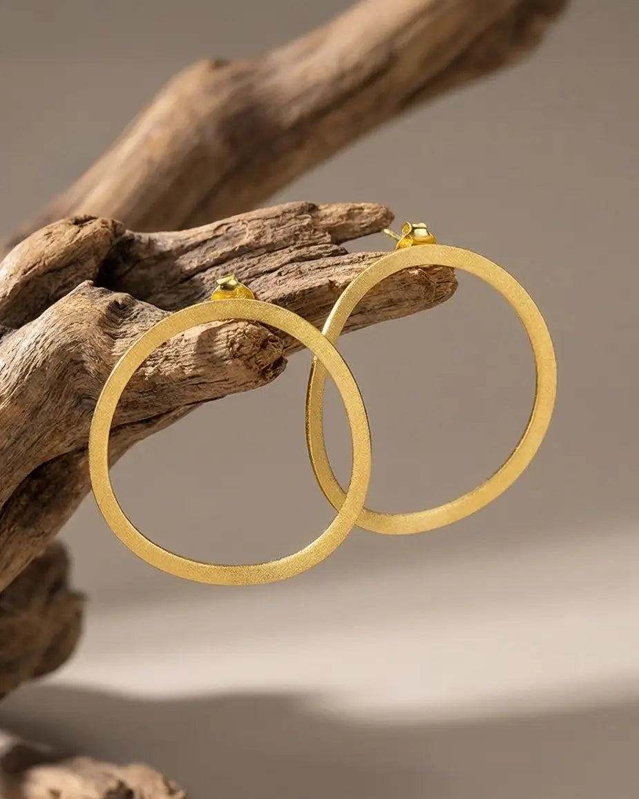 Créoles organiques en argent 925 avec finition or, posées sur une branche naturelle, style épuré et organique.