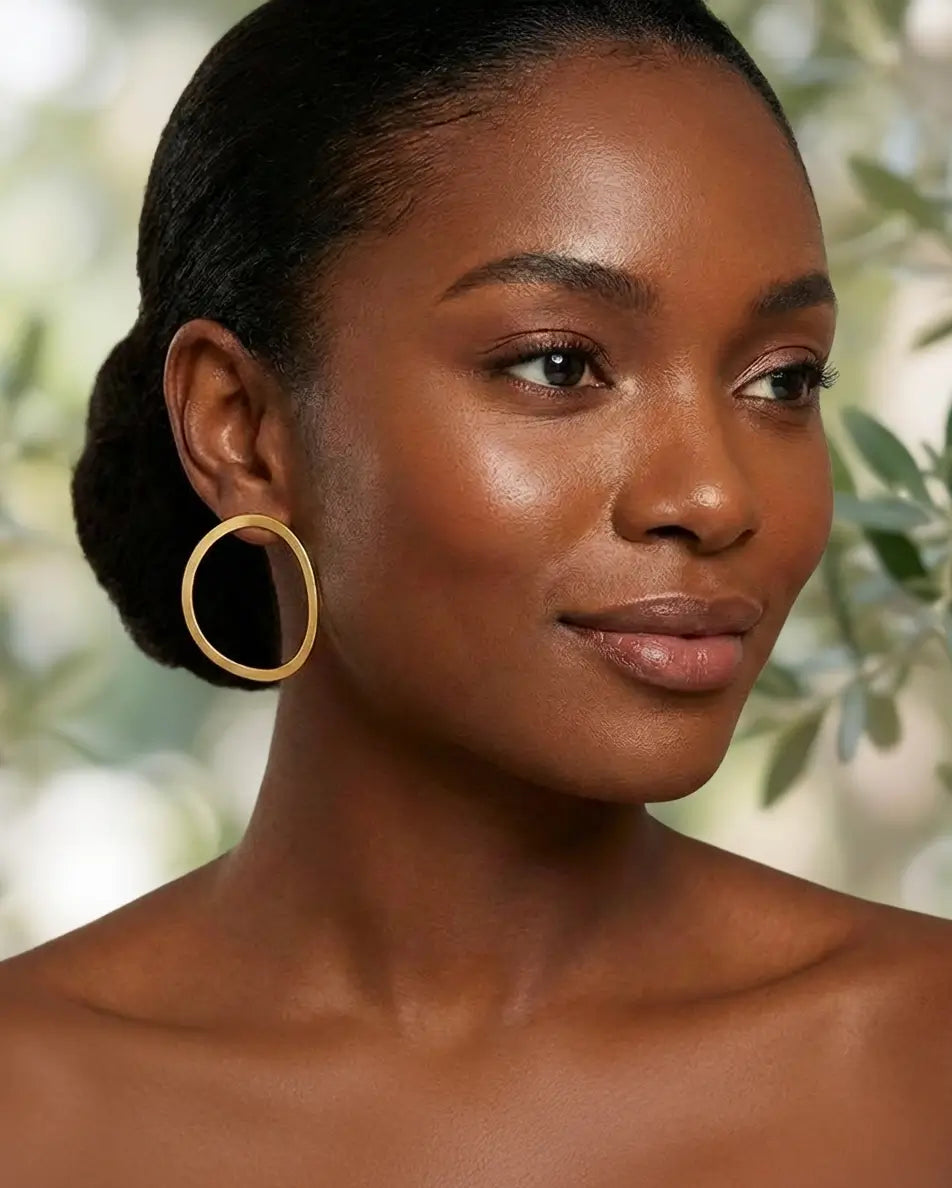 Créoles organiques en argent 925 avec finition or portées par une femme, bijou élégant au design arrondi et naturel.