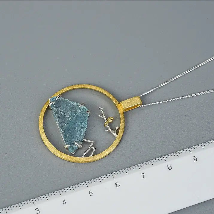Médaillon Envol du Sommet en argent et or présenté avec une règle pour visualiser les dimensions du pendentif.