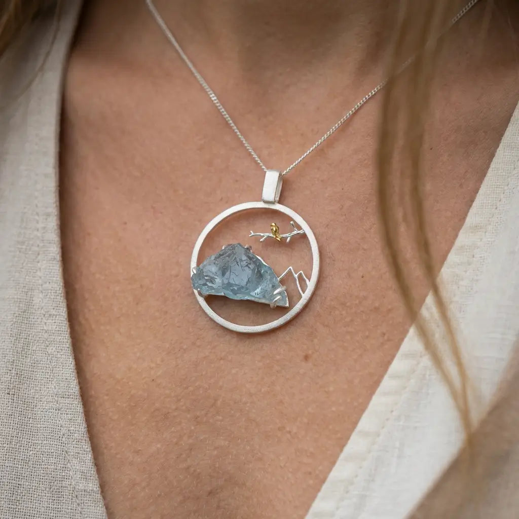 Médaillon Envol du Sommet en argent et or porté au niveau du buste, mettant en valeur la forme circulaire et la pierre naturelle.