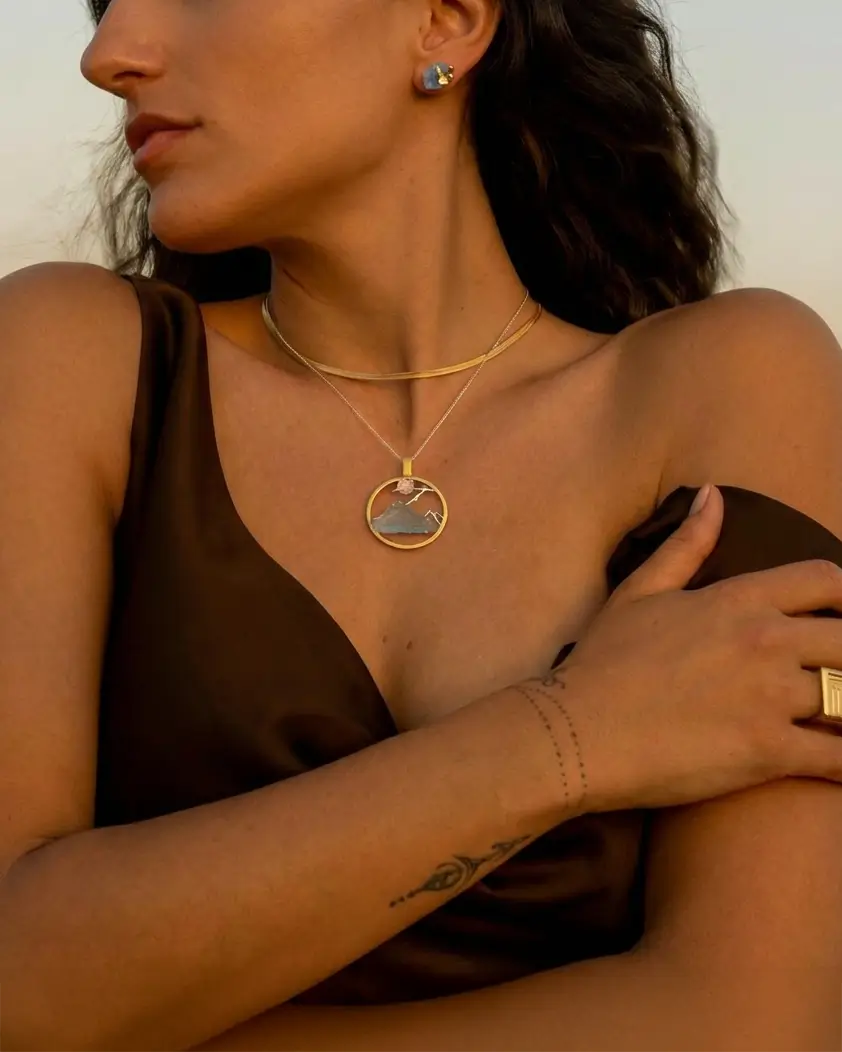 Médaillon floral du sommet en argent et or porté par une femme, bijou circulaire élégant et lumineux.